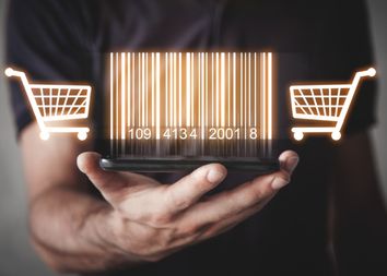 Über einer Hand schweben als Lichtbild ein Barcode mit zwei Einkaufswagen